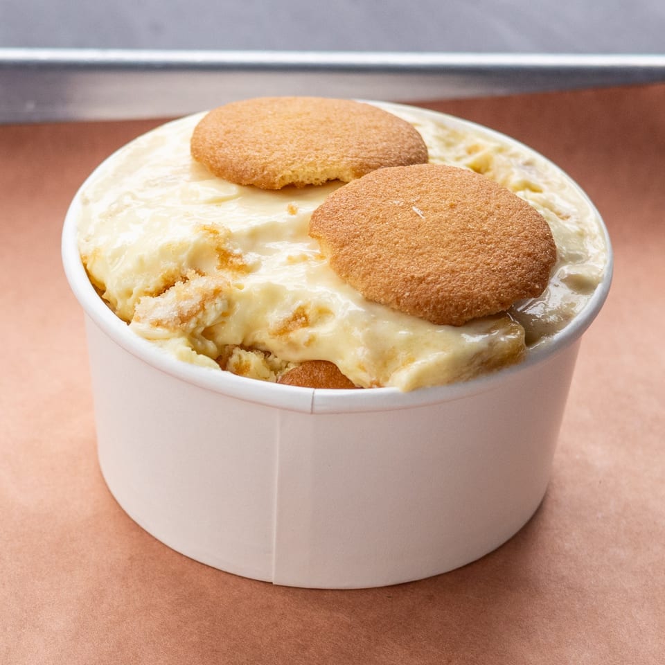 Banana pudding with vanilla wafers in a white cup from Hudson Smokehouse bx.
